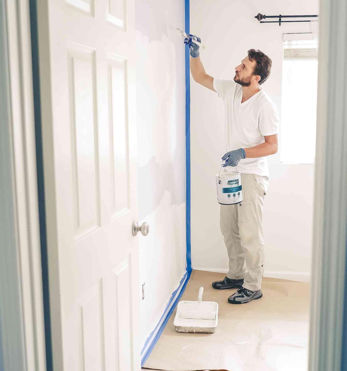 Man painting wall with Grizzly Coatings Anti-Mould paint in White Matt